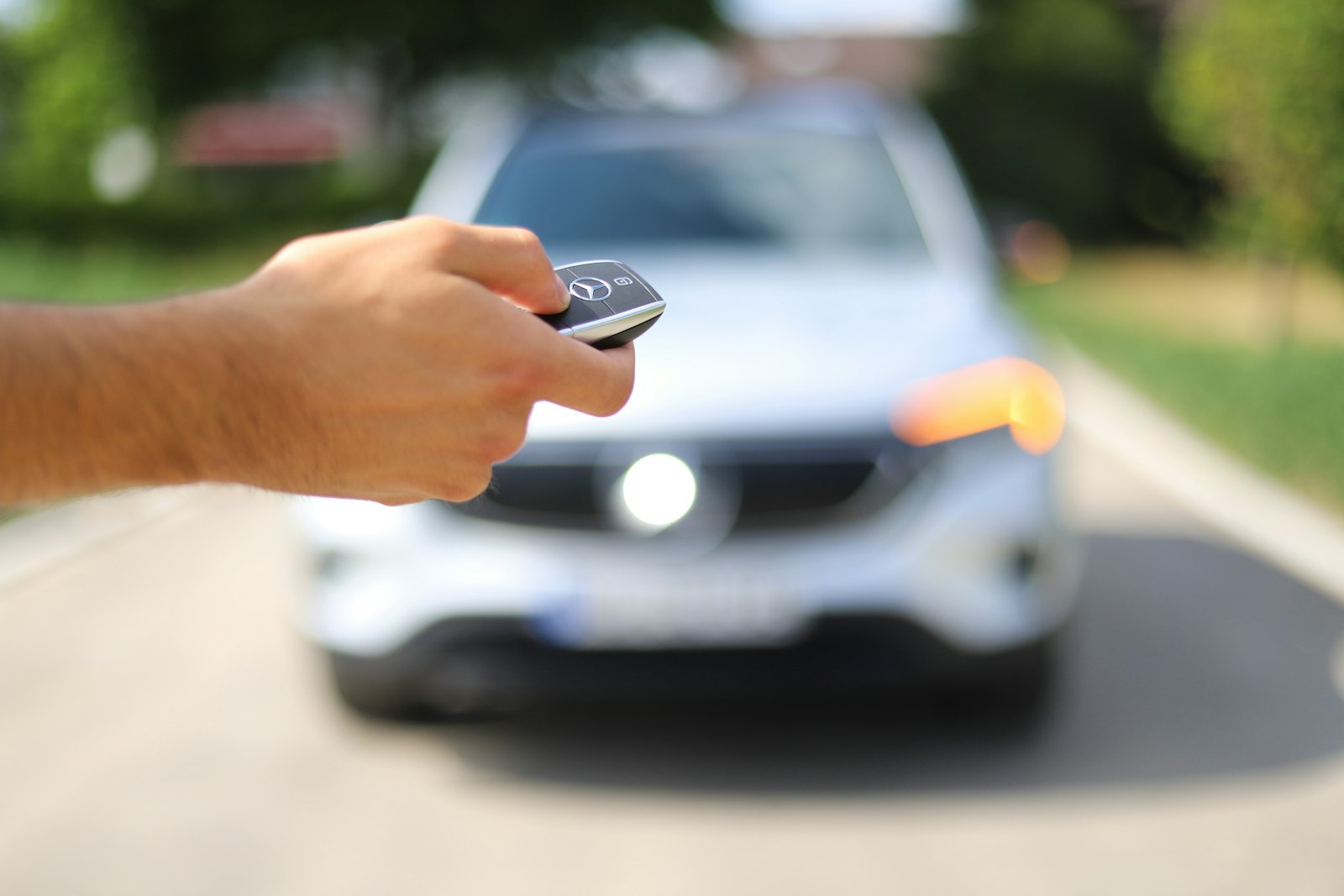 Hand pressing a car key fob toward a car